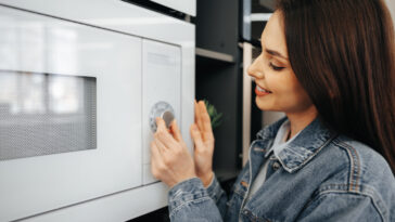 close de uma mulher verificando um novo forno de micro ondas em um hipermercado