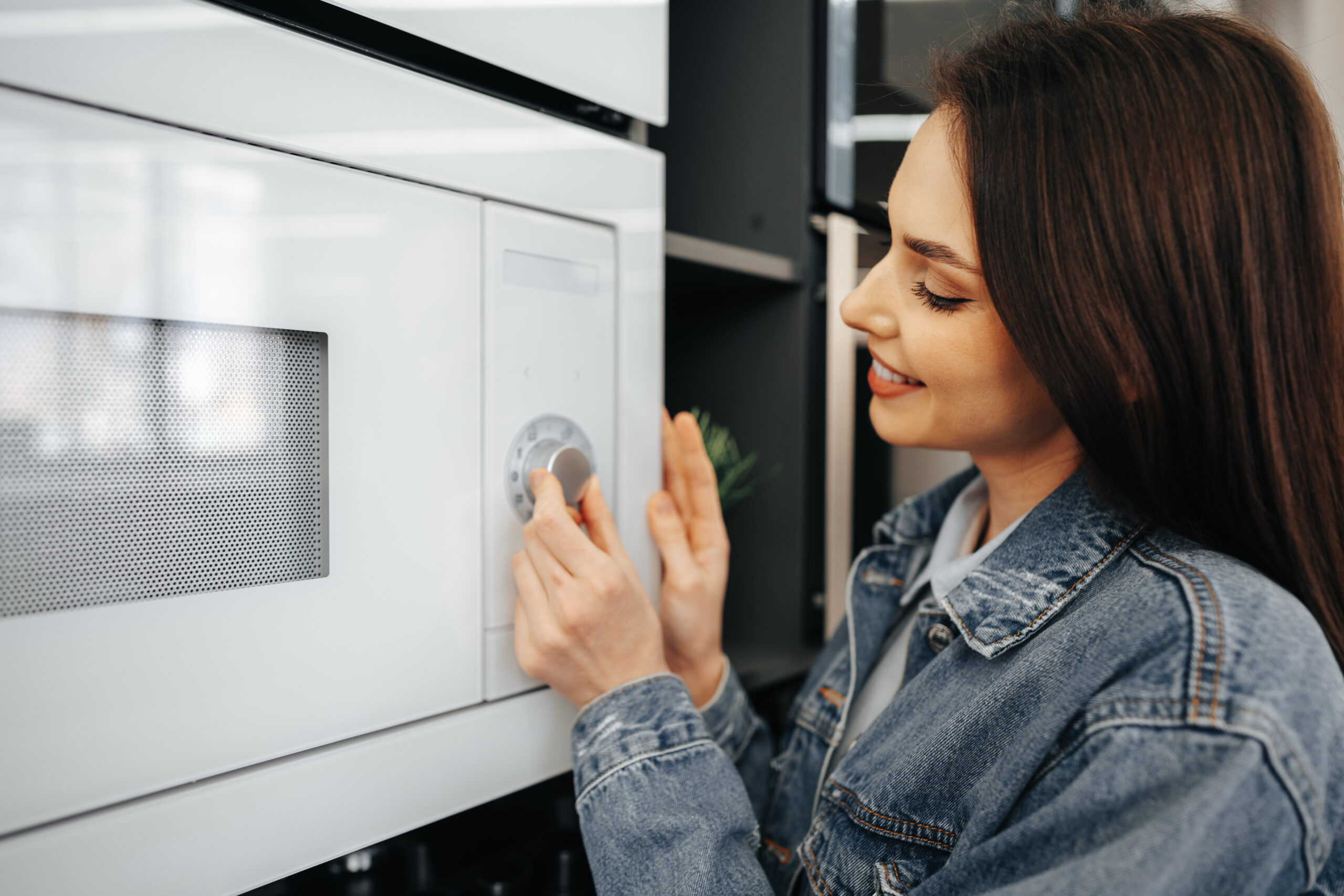 close de uma mulher verificando um novo forno de micro ondas em um hipermercado scaled